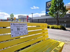 Yellow bench in foreground. Background is the Murray Bridge marketplace with the paved pedestrian crossing inbetween.